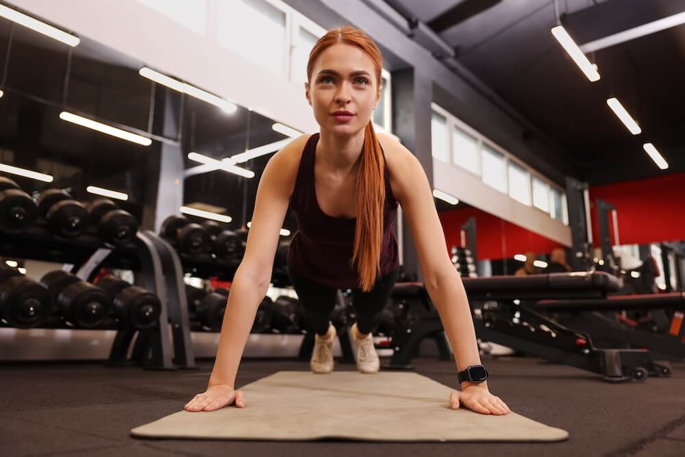 Woman doing pushup at gym showing red light therapy boosts athletic performance