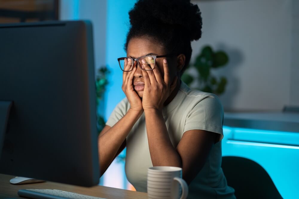 Tired woman staring at a computer with hands on her eyes dealing with inflammation fatigue and stress