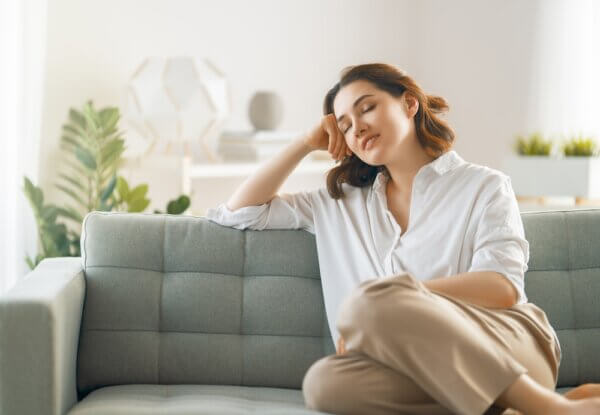 Woman sitting on couch looking relaxed after Vibroacoustic Therapy