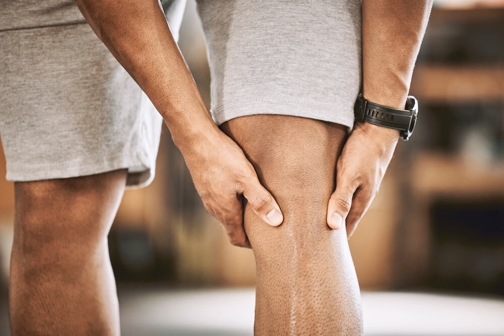 hands holding knee in pain needing muscle recovery under red light