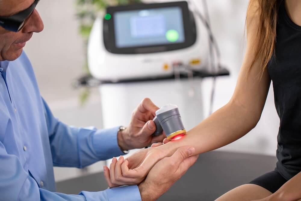 Provider giving class IV laser therapy to woman on her wrist