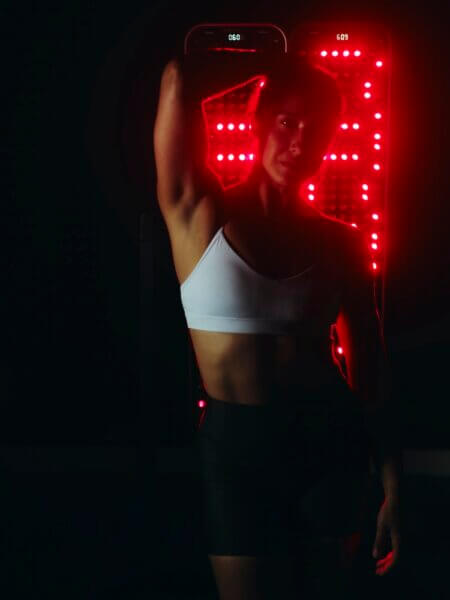 Woman standing in front of red light therapy panel